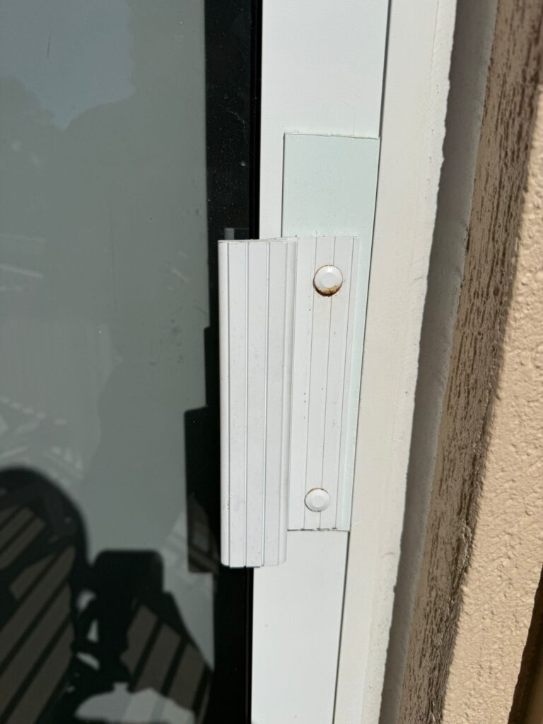 Salt-air corrosion forming around sliding door frame hardware in Florida coastal home