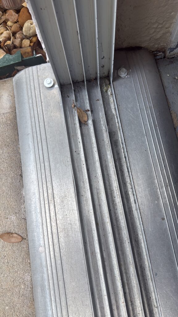 Clogged sliding door aluminum track with leaf debris before cleaning and repair in Florida