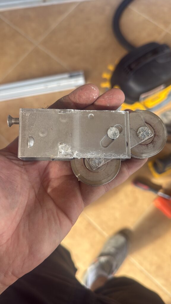 Alpha Sliding Doors technician holding worn calcified roller with DeWalt drill on job site